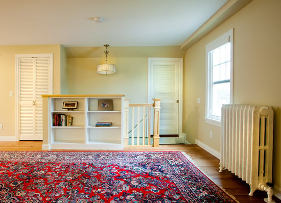 Remodeled attic with oriental rug and storage by Hanson Remodeling